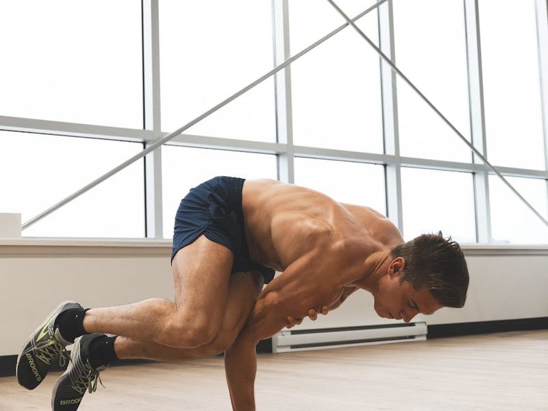 Man performing dynamic strength exercise in bright studio.